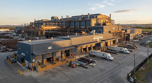 A sprawling industrial manufacturing facility with massive steel frameworks and safety-striped loading docks