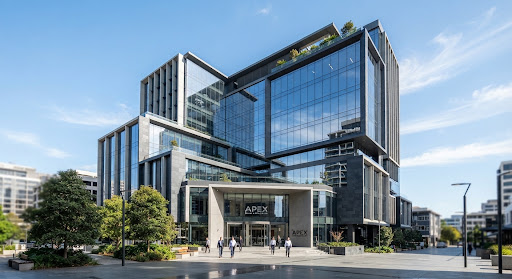 A modern multi-story office complex with expansive glass windows and dark slate structural elements
