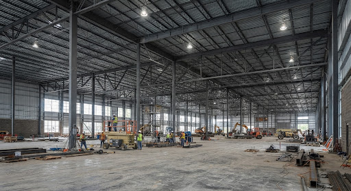 Interior view of a large industrial warehouse under construction with exposed steel girders